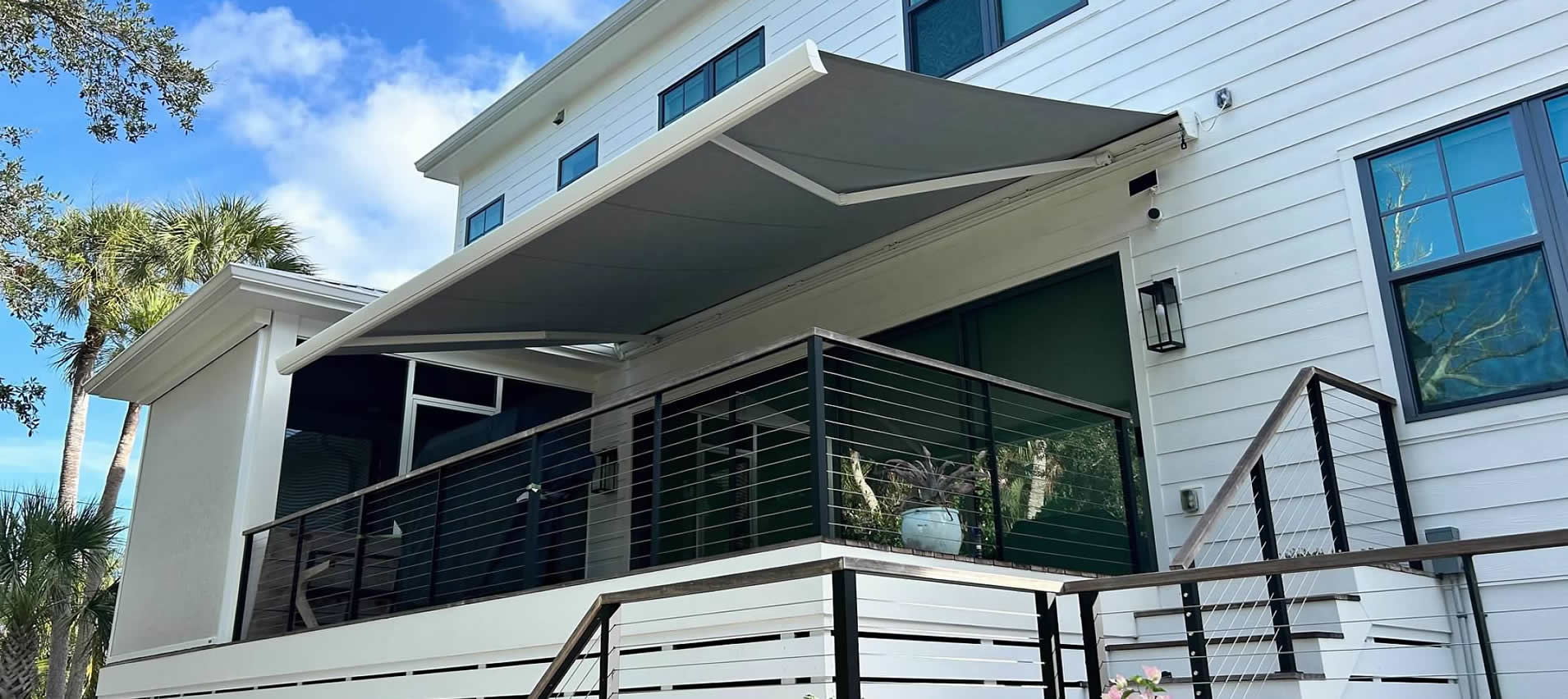 Retractable awning and screen room in Sarasota, Florida, with custom deck railing.